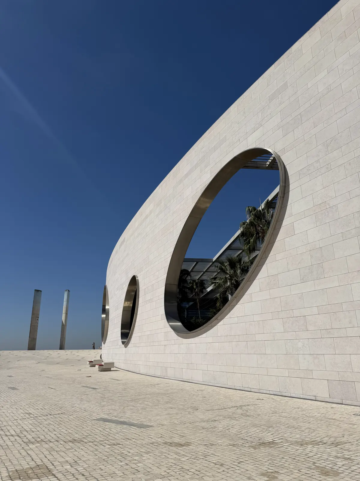 Curved white wall with huge round windows, against a deep blue sky.
