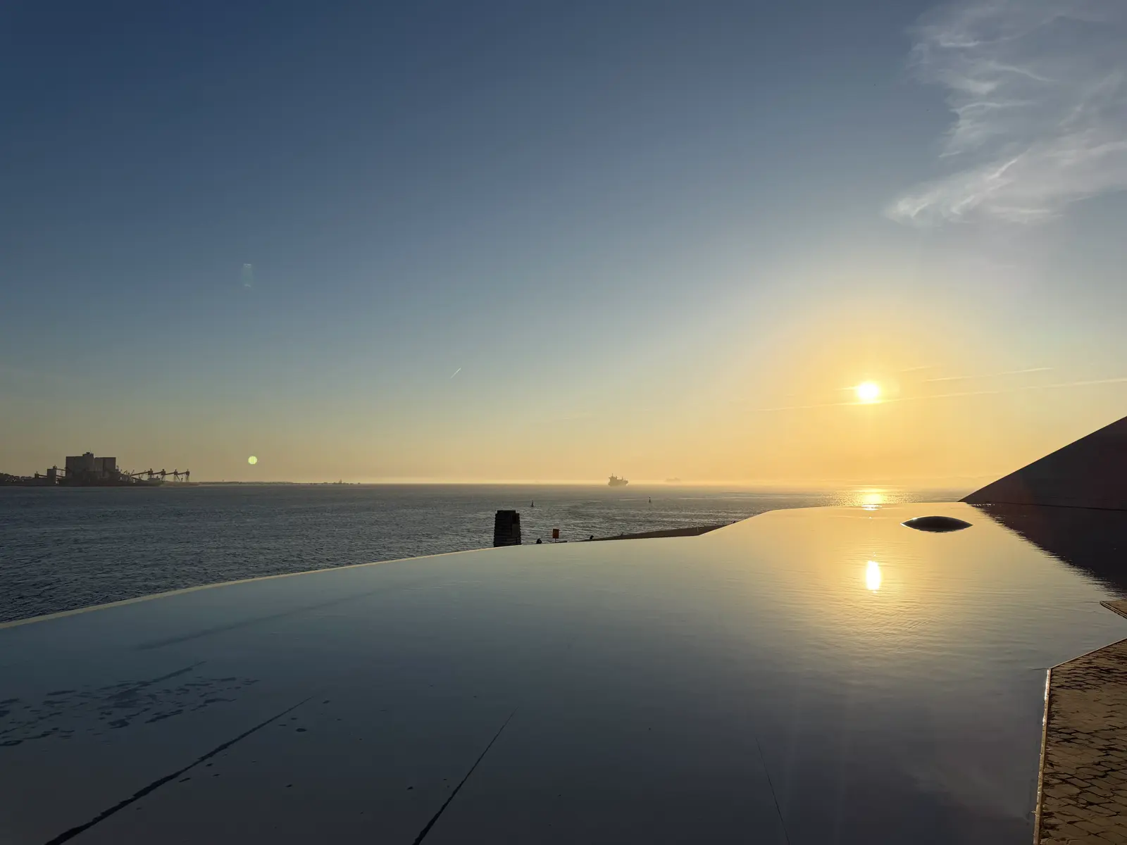 Sunset over the river, reflected in the pool, with the dark edge of the building on the right.