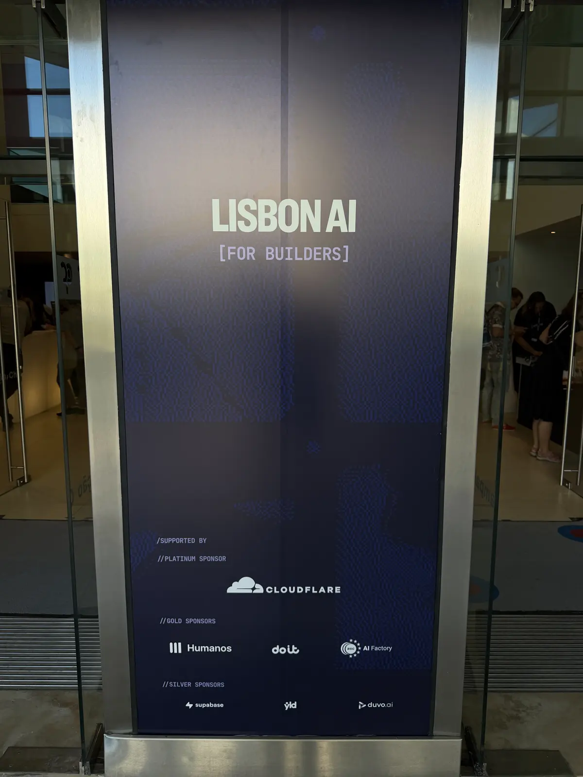 Dark totem at the entrance with the text LISBON AI [for builders] and sponsor logos.